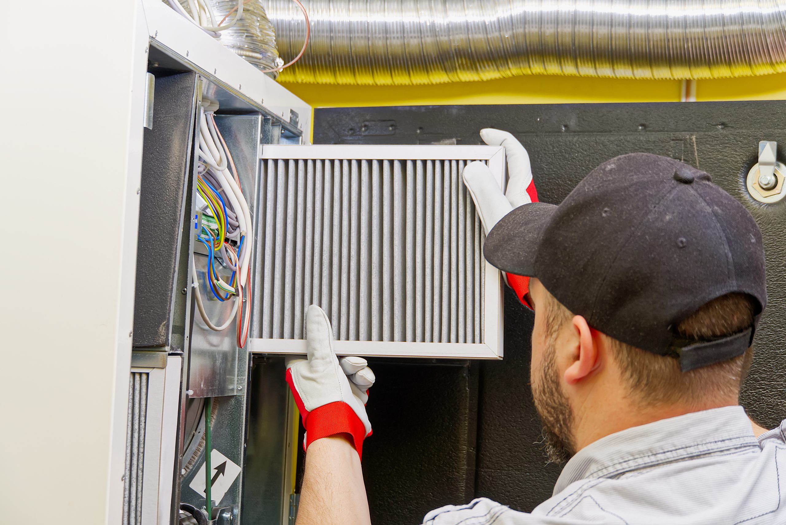 HVAC service technician changing dirty air filter in the central ventilation system